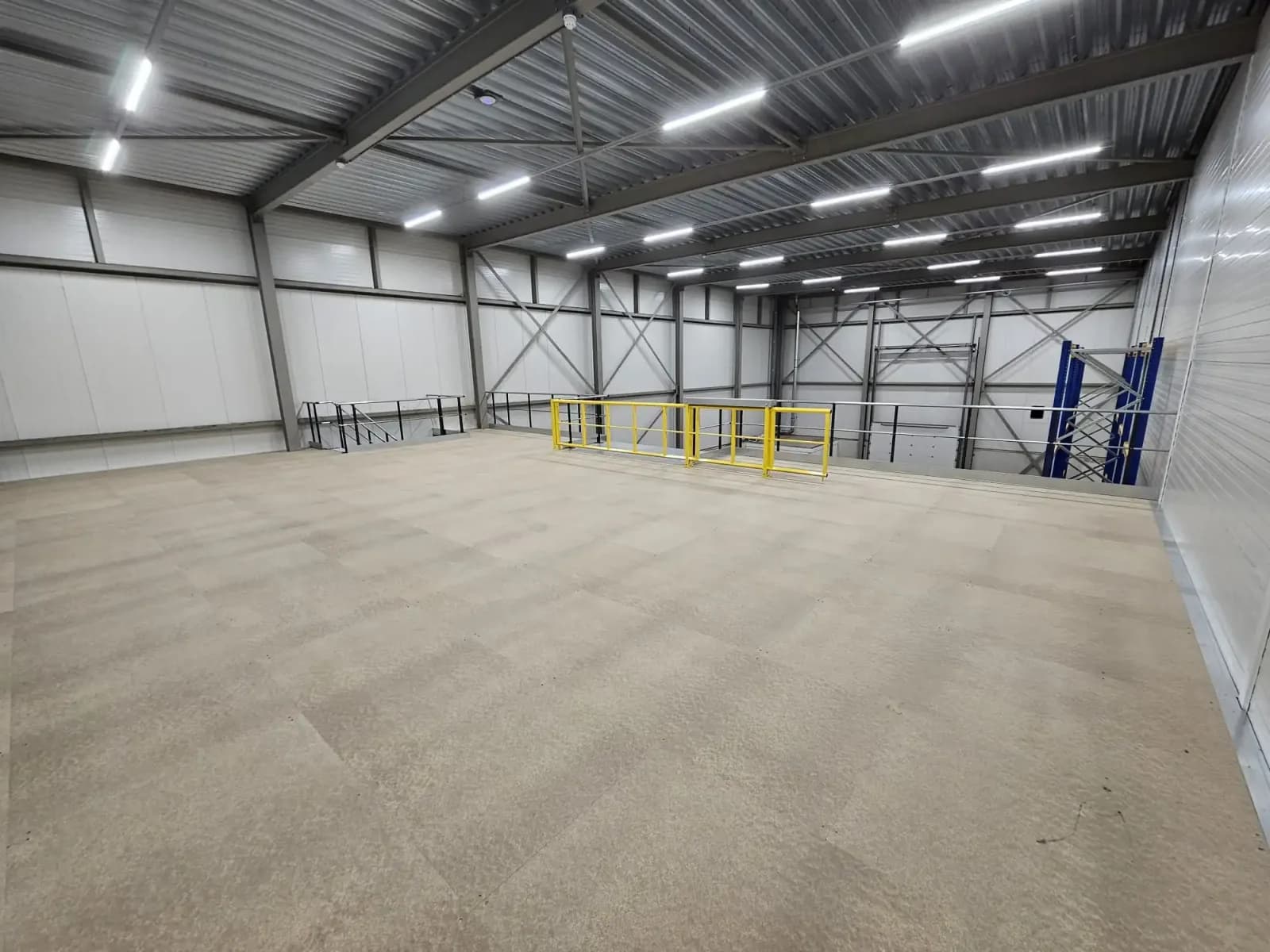 Completed mezzanine deck in a high-stud warehouse, with guardrail and pallet gate