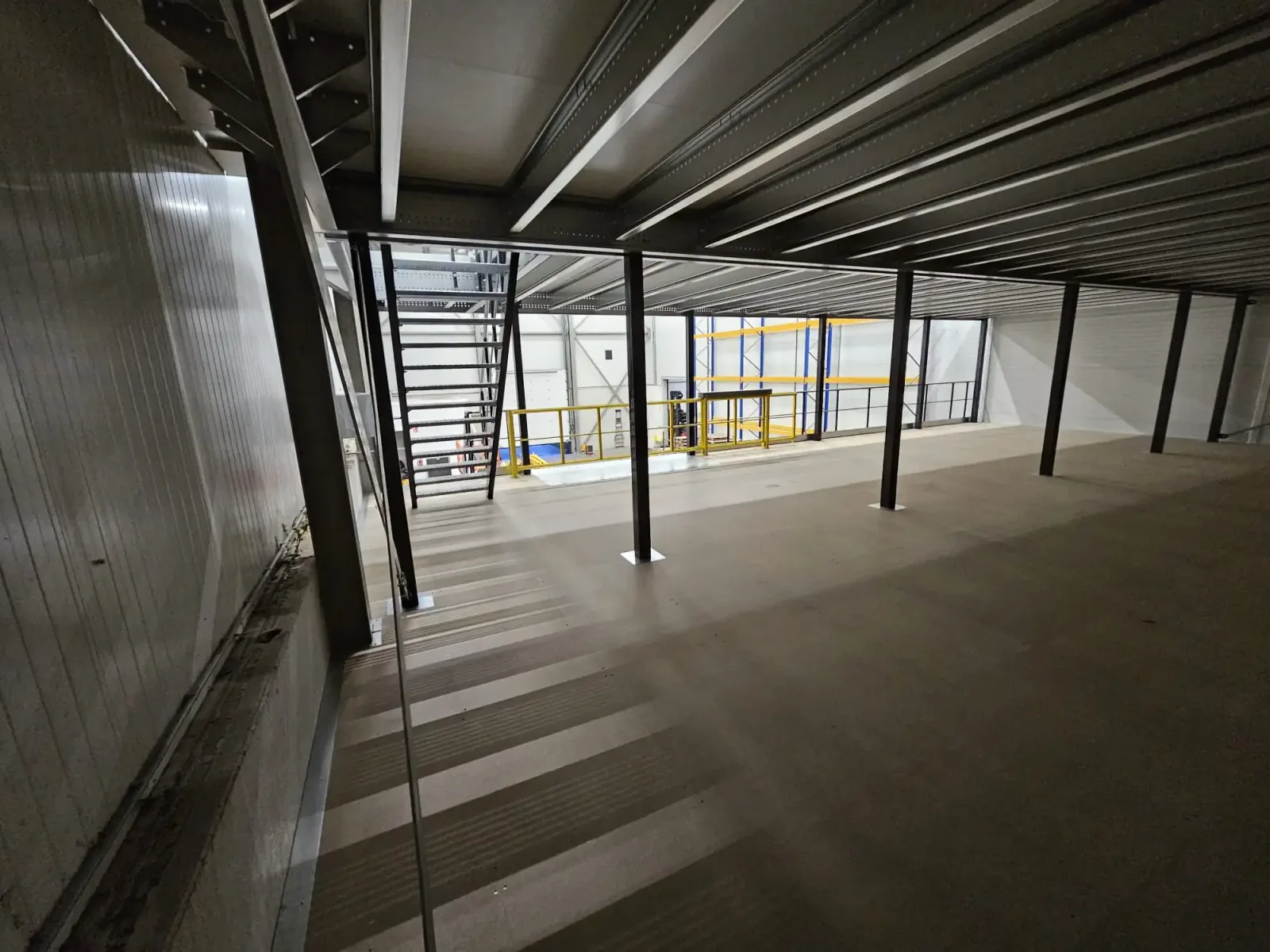 Underside of an installed steel mezzanine floor, showing beams and support columns
