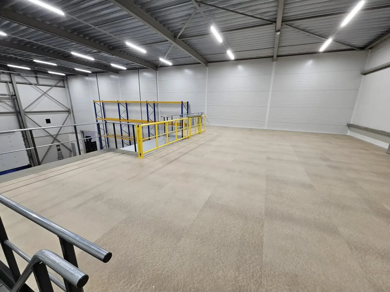 Mezzanine floor with pallet racking alongside and a yellow safety gate at the loading edge